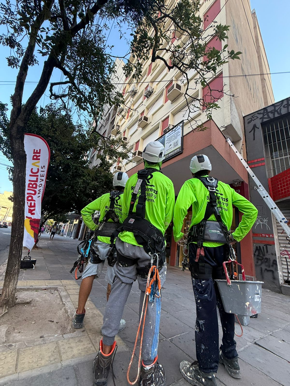 Equipe RL Reformas equipada com cintos de segurança em frente ao prédio