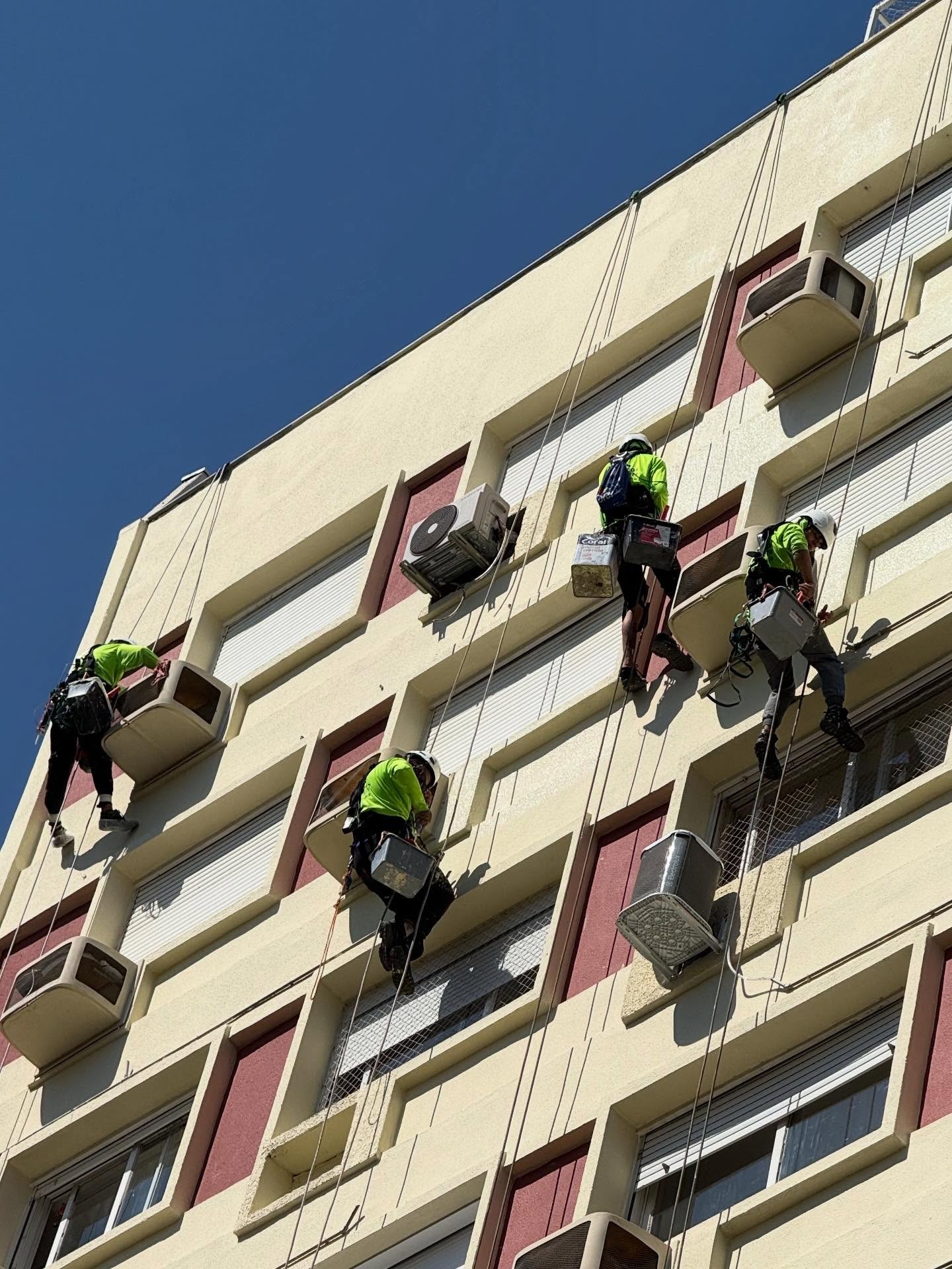 Equipe pintando fachada de prédio com rapel